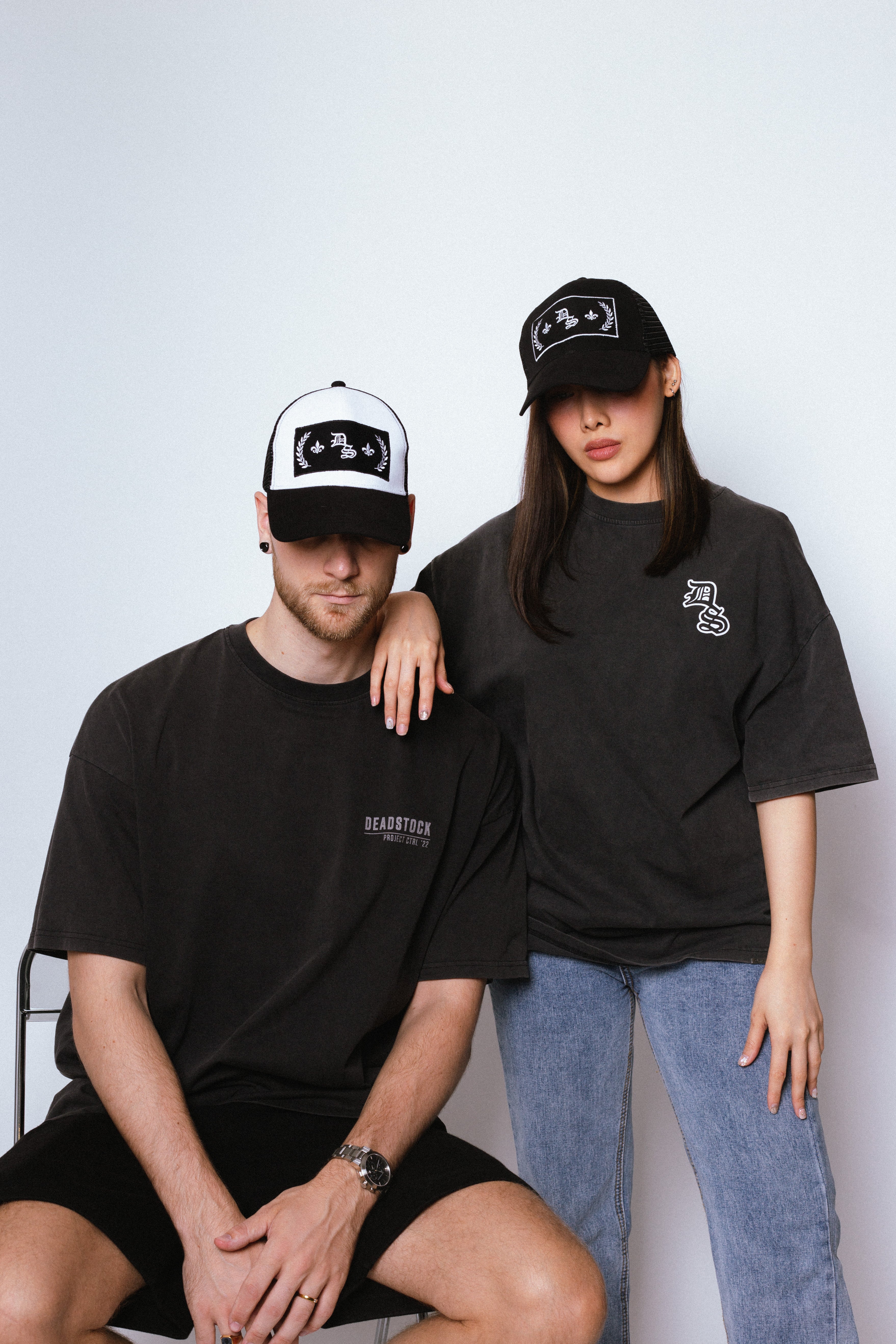A Male and Female Model wearing Deadstock Clo Conquerer Trucker Hat Black